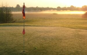 Ball near a golf hole on a golf course during sun set